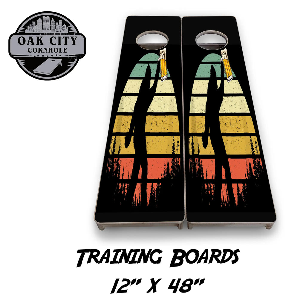 A cornhole board design featuring a silhouette of Bigfoot holding a beer mug against a vibrant, multicolored sunset background with trees at the bottom. The design showcases a playful and adventurous theme, perfect for outdoor gatherings and tournaments. 