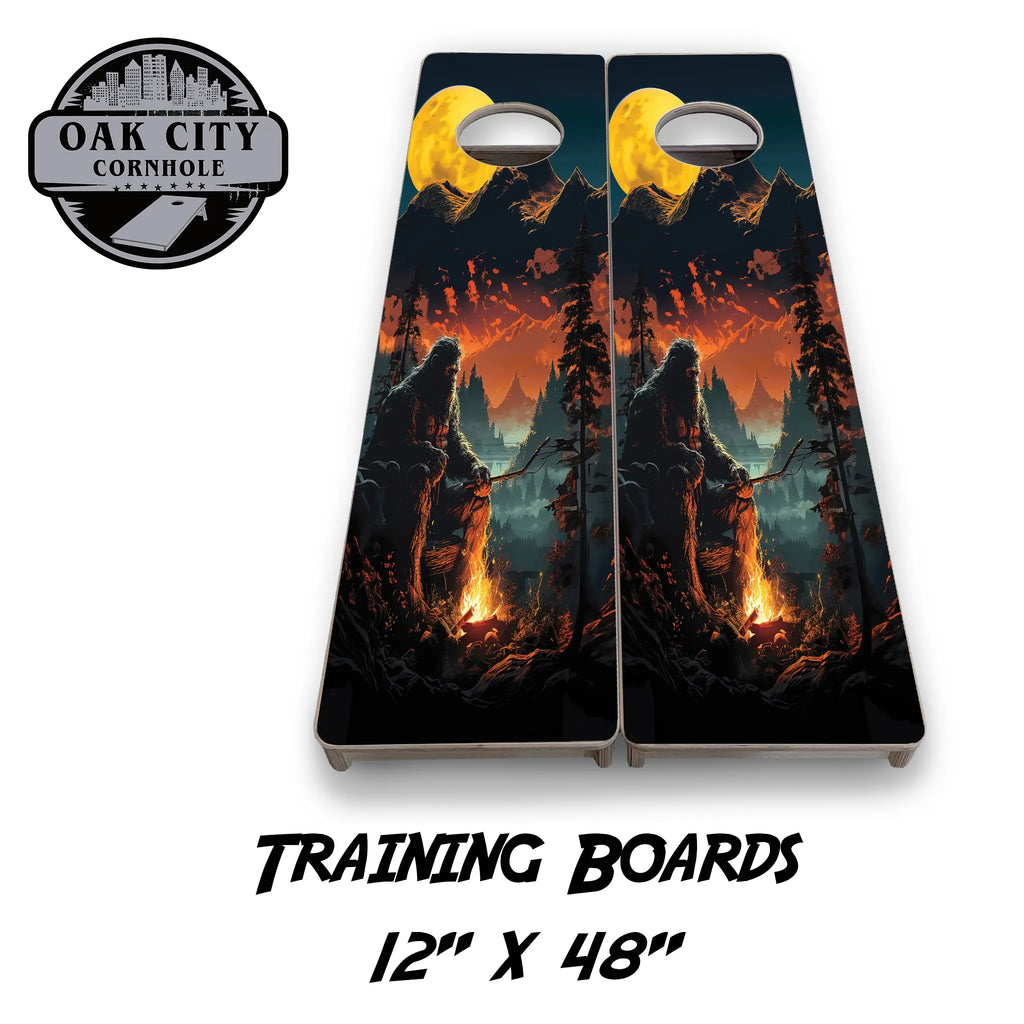 Premium handcrafted 24x48 cornhole boards featuring a 'Bigfoots Campfire' design from Oak City Cornhole. Perfect for tournaments with a high-resolution image of Bigfoot by a campfire in the woods.